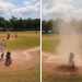 Niño queda en el centro de un remolino de arena durante partido de béisbol